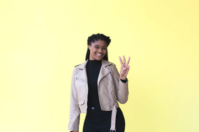 Portrait of young man standing against yellow background