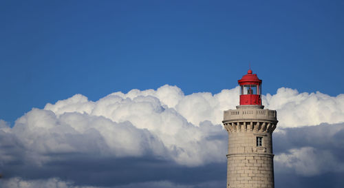 Low angle view of lighthouse by building against sky