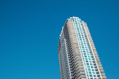 Low angle view of skyscrapers against blue sky