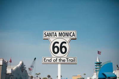 Low angle view of road sign at santa monica pier against clear sky