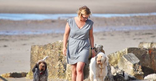 Young woman with dog standing at beach
