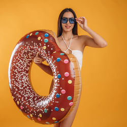 Portrait of woman wearing sunglasses against yellow background