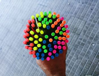 Cropped hand of person holding multi colored pencils