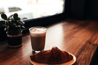 Cup of coffee, croissant at table near the window in cafe. blurred background. high quality photo