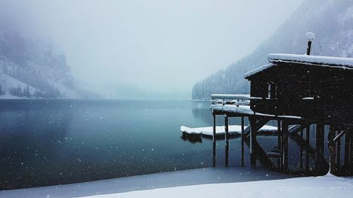 Scenic view of lake by building against sky during winter