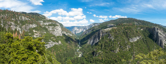 Panoramic view of green rocky mountains against sky on sunny day