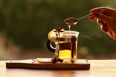Person pouring drink in glass container on table