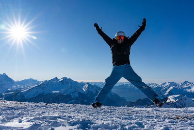 Girl with arms raised on snowcapped mountain against sky