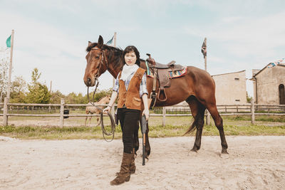 Portrait of woman standing with horse at ranch