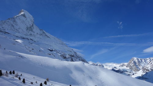 Scenic view of snowcapped mountain against blue sky