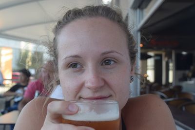 Close-up of smiling young woman with beer glass sitting in restaurant 