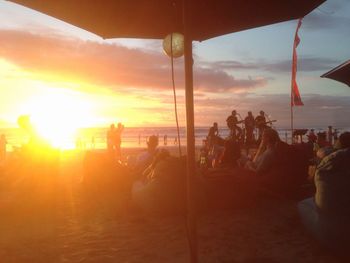 People and musicians at beach during sunset