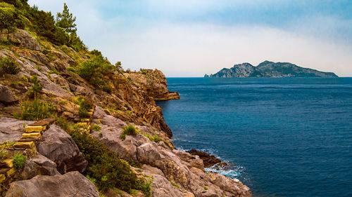 Scenic view of rocks by sea against sky