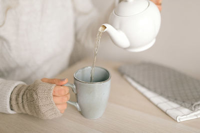 Close-up of hand pouring tea cup