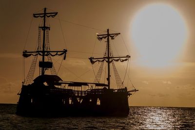 Silhouette sailboat in sea against sky during sunset