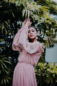 Young woman standing against plants