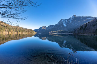 Scenic view of lake and mountains against clear blue sky