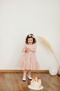 A cute little girl is standing next to a cake for her birthday. holiday, birthday, cake, gifts