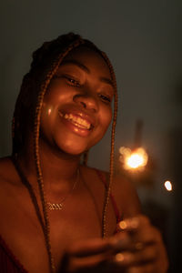 Portrait of young woman standing against black background