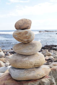 Stack of pebbles on beach against sky