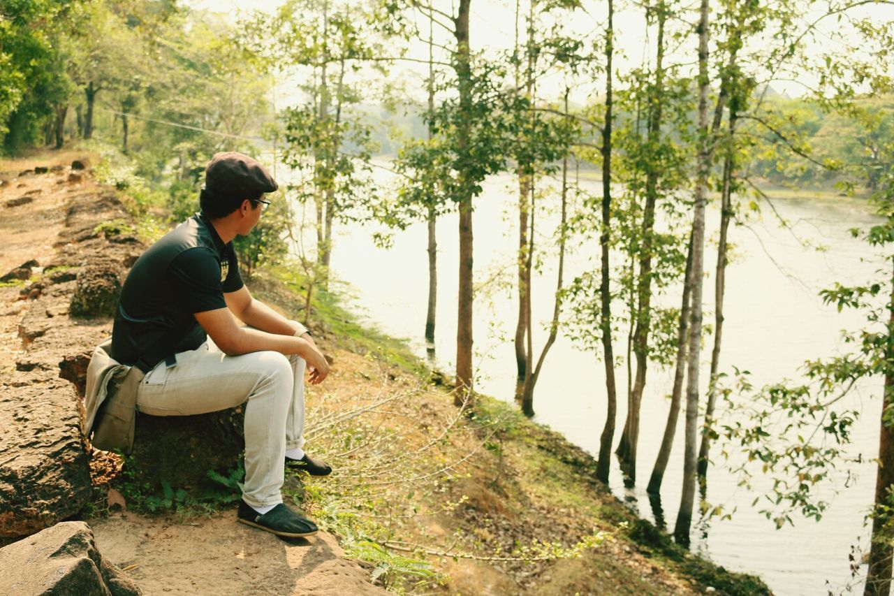 tree, lifestyles, leisure activity, water, casual clothing, full length, sitting, lake, tranquility, rear view, tranquil scene, relaxation, nature, men, standing, young adult, beauty in nature, scenics