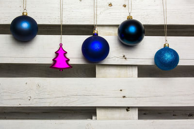 Christmas ornaments hanging against white wooden fence