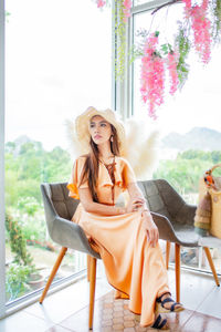 Young woman sitting on chair against plants