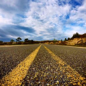 Surface level of road against cloudy sky