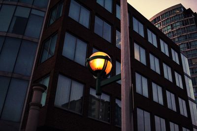 Low angle view of illuminated street light against building at night