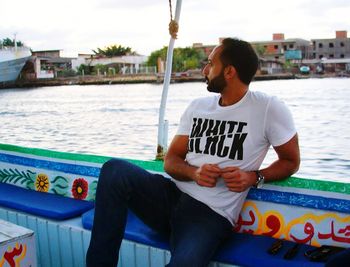 Man sitting in sea with city in background