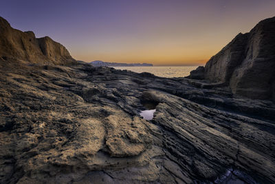 Rock formations in sea against sky during sunset