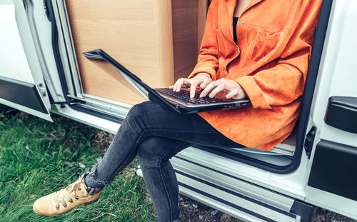 Woman teleworking sitting in the door of campervan