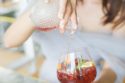Midsection of woman pouring drink in glass