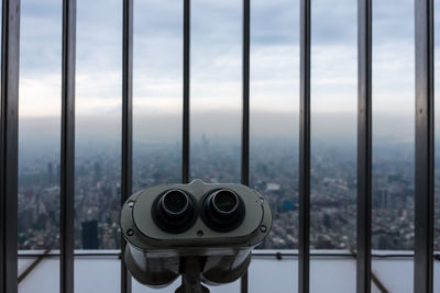 Close-up of coin-operated binoculars against cityscape