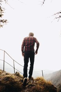 Rear view of man standing on field against sky