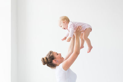 Side view of mother and daughter against white wall