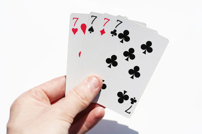 Close-up of hand holding playing cards over white background