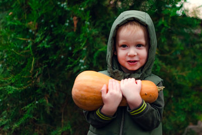 A little boy in a green jacket with a pumpkin in his hands. harvest. preparations for halloween.