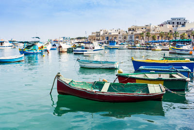 Boats moored at harbor against sky