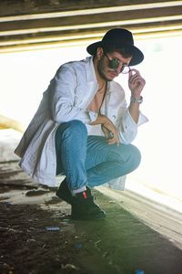 Full length of young man sitting on mobile phone