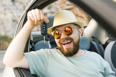 Portrait of young man using mobile phone while driving car