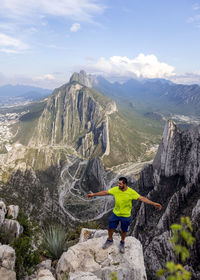 Man standing on rock against sky