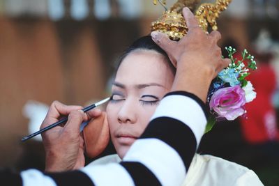 Cropped image of artist applying make-up on young woman