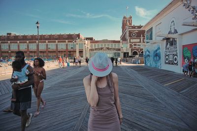 People walking on boardwalk at beach in city