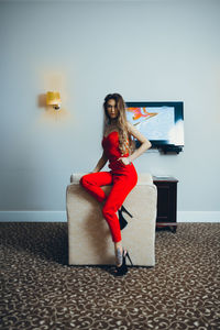 Full length portrait of young woman sitting on floor