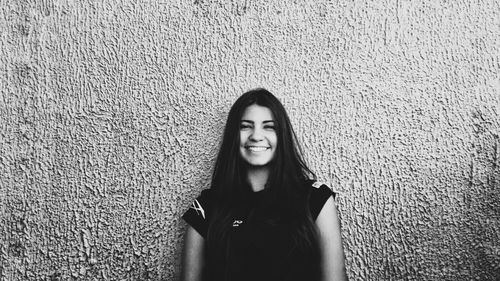 Portrait of beautiful young woman standing against wall