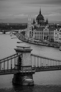 Bridge over river in city against sky