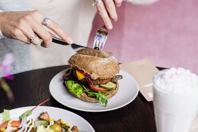 Midsection of woman having burger at table