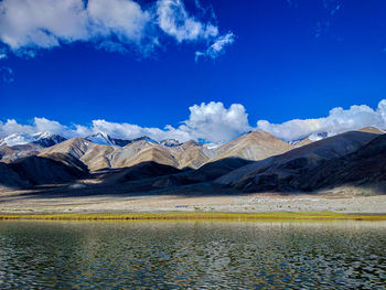 Scenic view of lake by mountains against blue sky