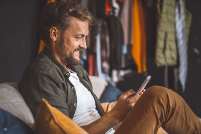 A man sitting on a couch, engrossed in his cell phone.